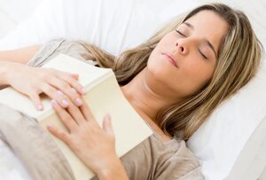 Beautiful woman falling asleep while reading a book