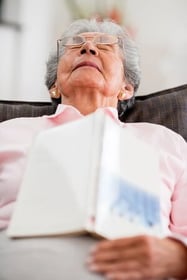 Elder woman falling asleep while reading a book