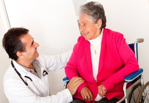 Elder woman sitting in a wheelchair at the hospital talking to the doctor
