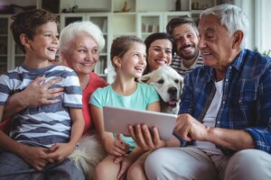 Happy multi-generation family using digital tablet in living room at home