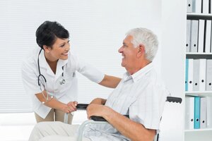 Side view of a female doctor talking to senior patient in wheelchair at the hospital