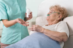 Young nurse giving the pills to her sick older patient