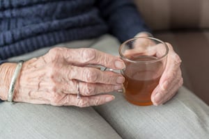 older woman holding mug of hot tea on her lap0