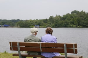 Older couple sitting together and talking on a bench outdoors