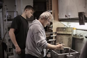 older man showing apprentice how to complete work 