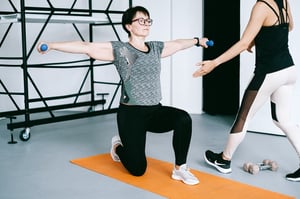 older woman exercising with the help of a professional