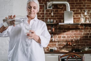 older woman pouring a glass of water in kitchen