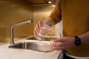 man pouring water at sink with fitness tracker watch