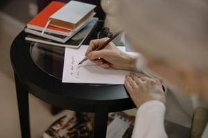 older woman writing letter by hand at table