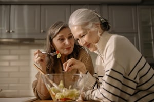 older woman talking with friend while eating salad
