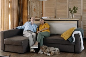 older couple sitting on couch with dog at their feet