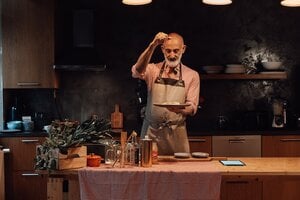 older gentleman preparing food alone in kitchen