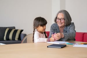 grandmother helping teach her granddaughter at table