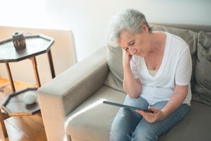 senior woman, sad spending time alone on tablet
