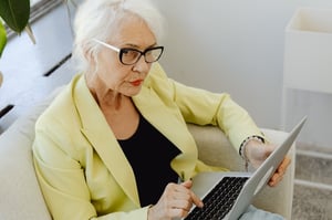 senior woman sitting in chair with laptop