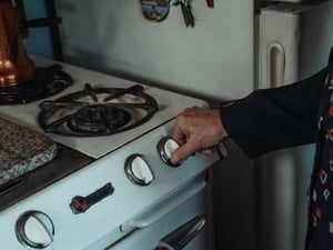 older woman turning on stove