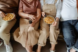 older adults eating popcorn on a couch 