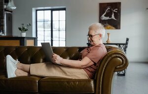 older woman on couch with laptop, social media 