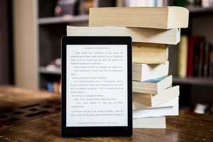 tablet e-reader on table in front of books