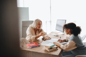 older woman tutoring young student at desk