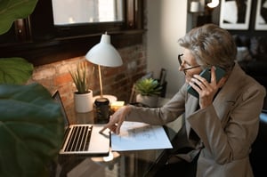 older woman talking on phone and using laptop