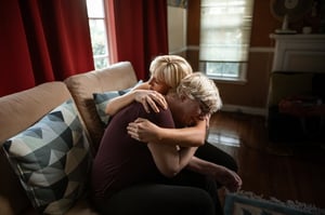 sad older woman hugging family member
