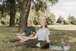 Older couple meditating outdoors