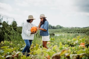 grandmother and granddaughter picking pumpkins together 